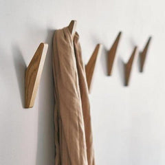 Tweekleurige houten wandhaken aan een lichte muur